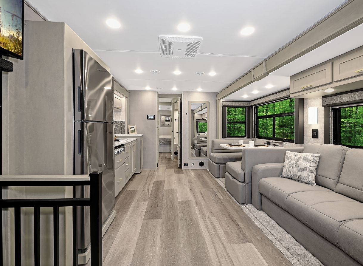 Interior of 2026 Renegade Valencia with light wood cabinetry, stainless steel appliances, a full kitchen on the left, and a living area on the right