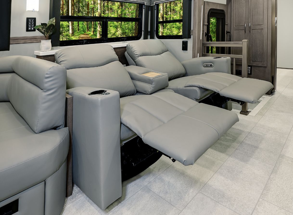 Dual reclining theater seats in the 2026 Renegade Explorer upholstered in gray leather. Built-in cup holders and wide windows create a cozy lounge space.