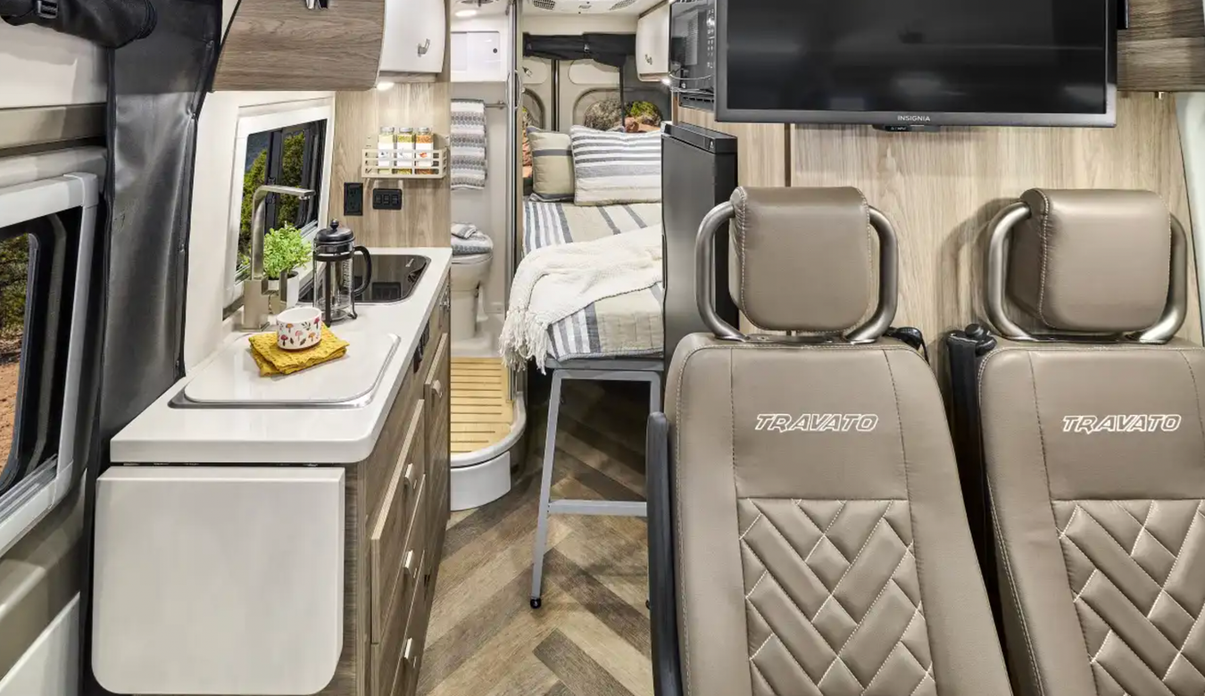 Interior shot of the Travato including seats, galley, and bed