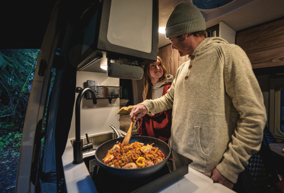 Two smiling travelers cook in the 2025 Tiffin GH1&#039;s galley