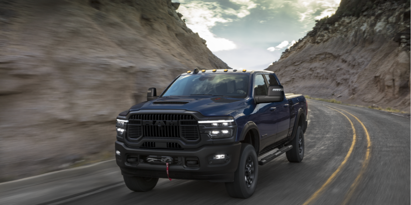 2025 2500 (DJ) Power Wagon in Forged Blue, driving on a highway surrounded by rocky cliffs.