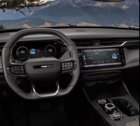 Interior of the 2026 Jeep Cherokee Limited showing the Uconnect 5 touchscreen, digital instrument cluster, and Jeep steering wheel with mountain views through the windshield