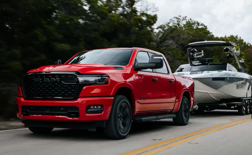 2026 RAM 1500 Big Horn 4x4 towing a boat on a highway