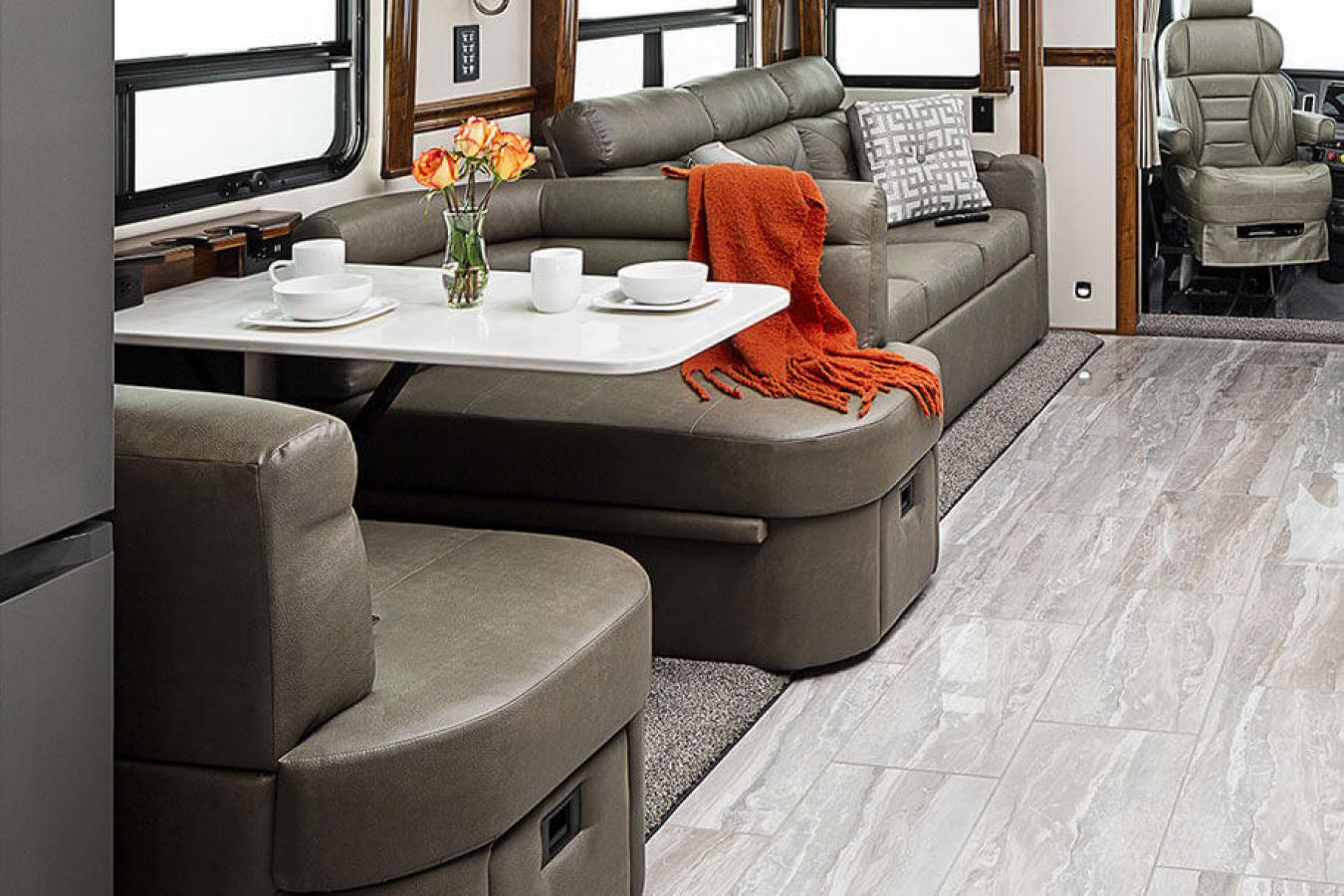 Gray seating area around a table with brown cabinets instead a Renegade RV