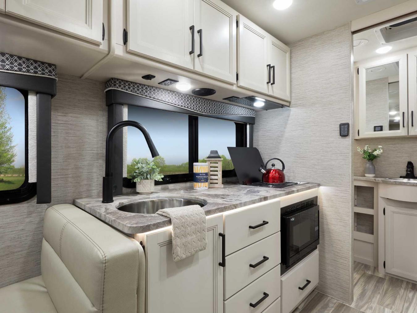 Kitchenette inside a Thor RV featuring a stovetop, round sink, and microwave