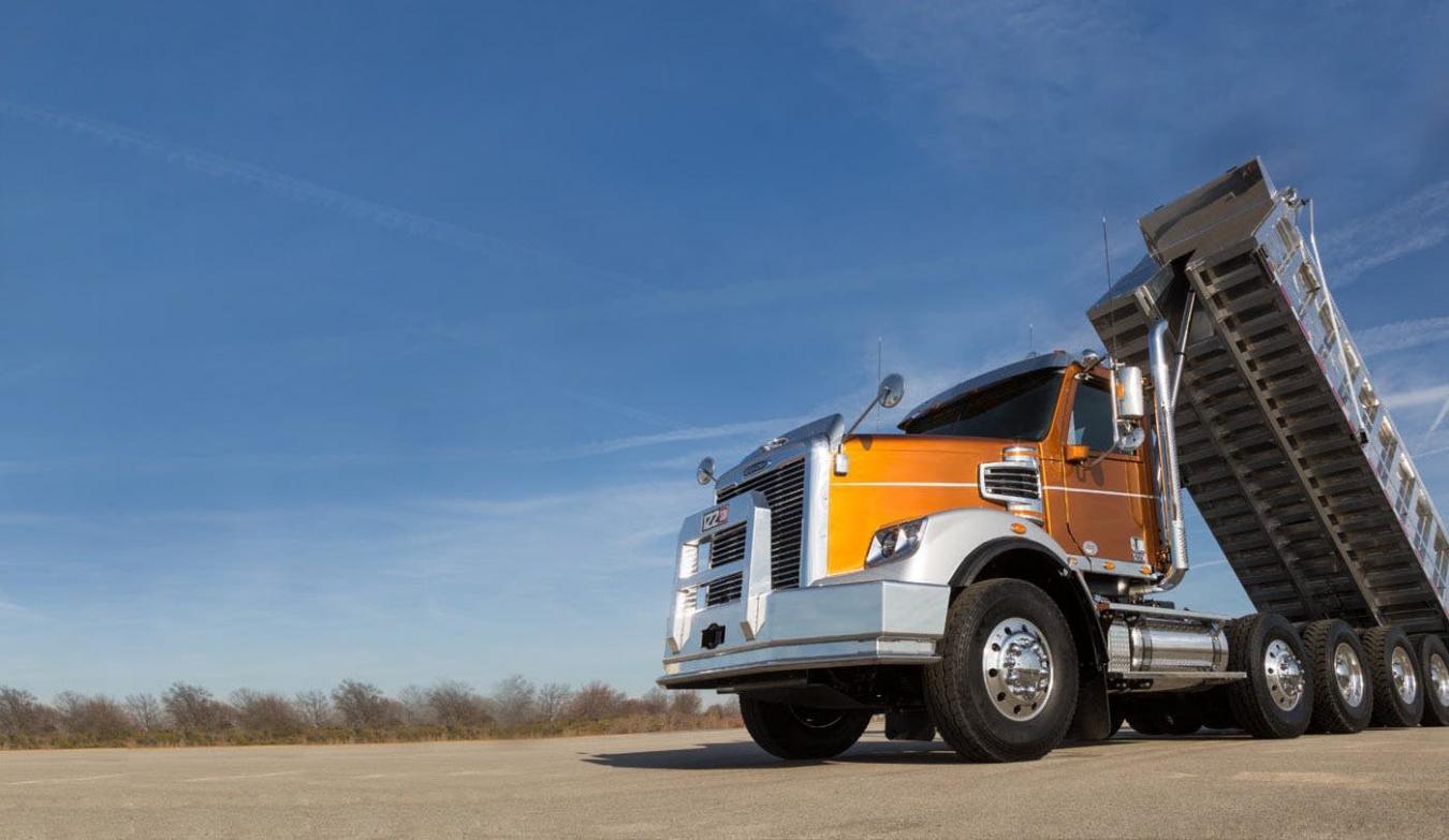 Orange Freightliner dump truck with trailer raised