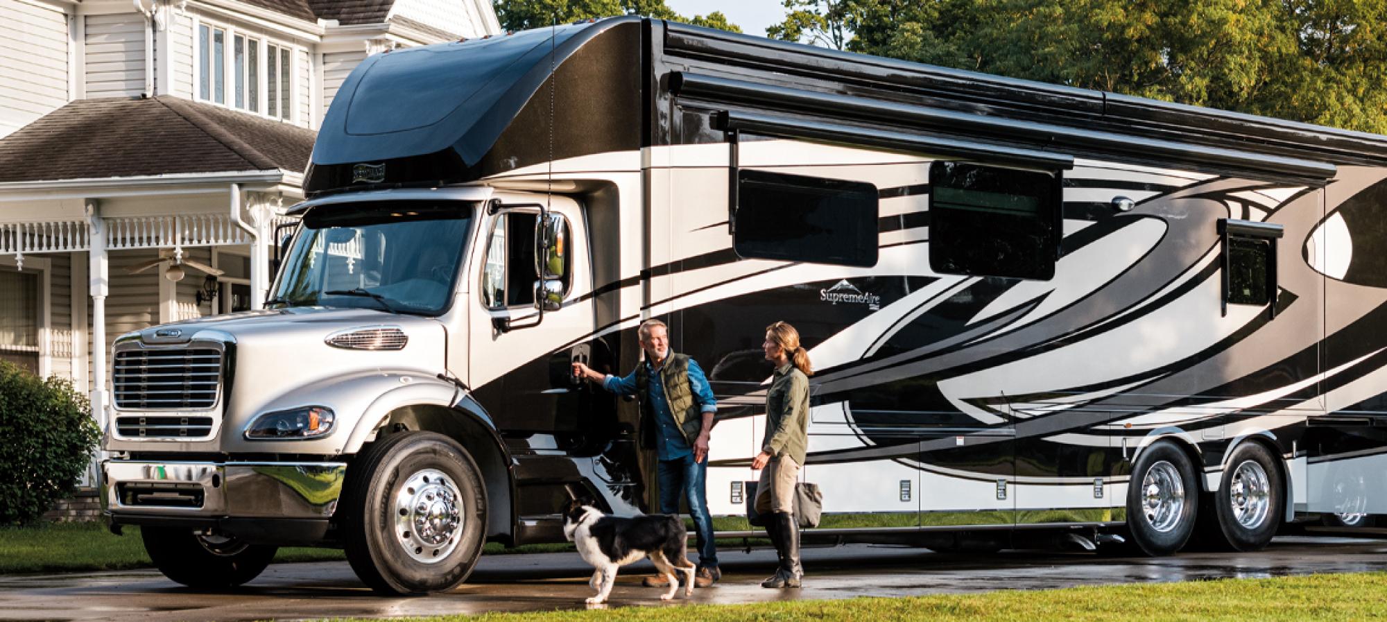 A couple and a dog standing outisde of a Newmar RV