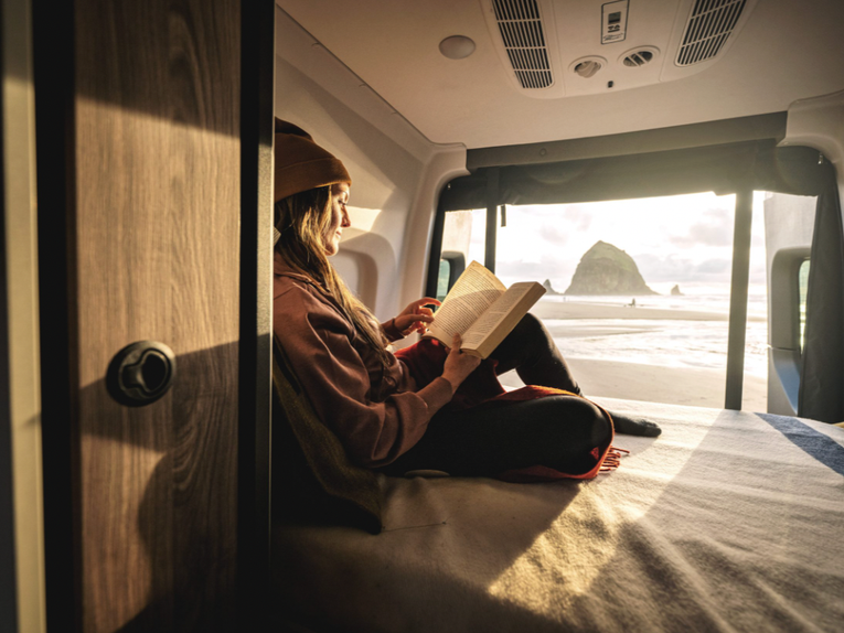 A traveler reads a book in bed on the 2025 Tiffin GH1