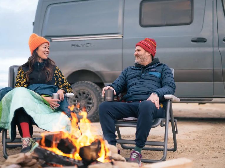Couple in front of a fire outside the Winnebago Revel