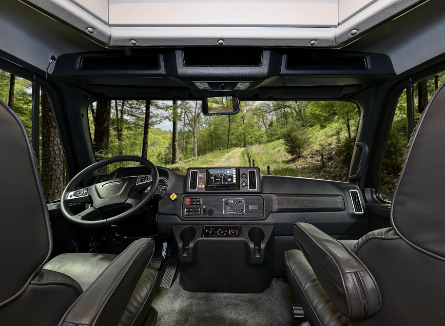 Front cab of a 2026 Renegade Valencia RV with leather captain’s chairs, steering wheel, and dashboard controls