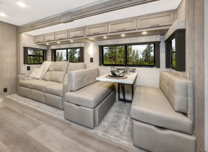 2026 Renegade Verona living space with leather sofa, booth dinette, and large panoramic windows.