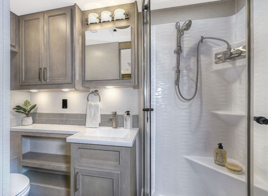 2026 Renegade Verona main bathroom with walk-in shower, vanity, storage cabinets, and decorative tile backsplash.