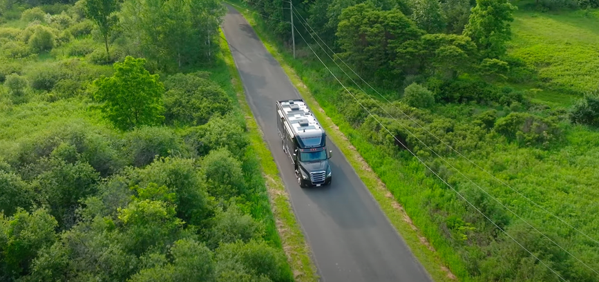 Bird&#039;s eye view of a 2025 Renegade Explorer driving on a road surrounded by trees