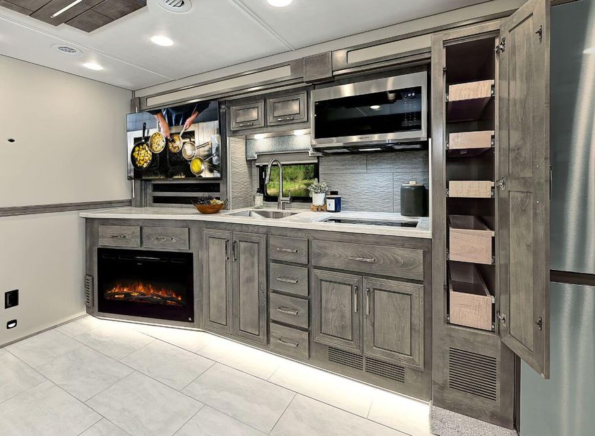 Kitchen cabinets, fireplace, microwave, TV, and sink in the 2025 Renegade Explorer