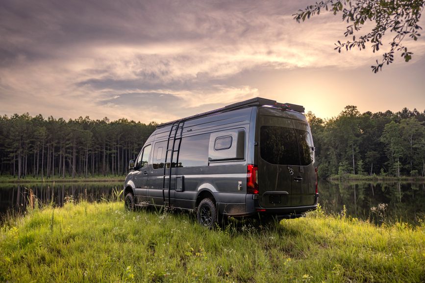 An exterior shot of the Tiffin GH2 from behind as it faces a lake or pond
