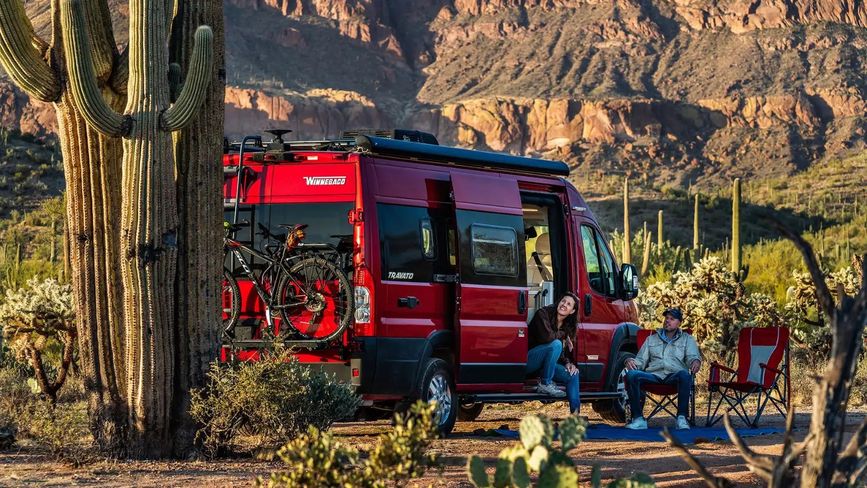 A couple outside the Travato in a desert 