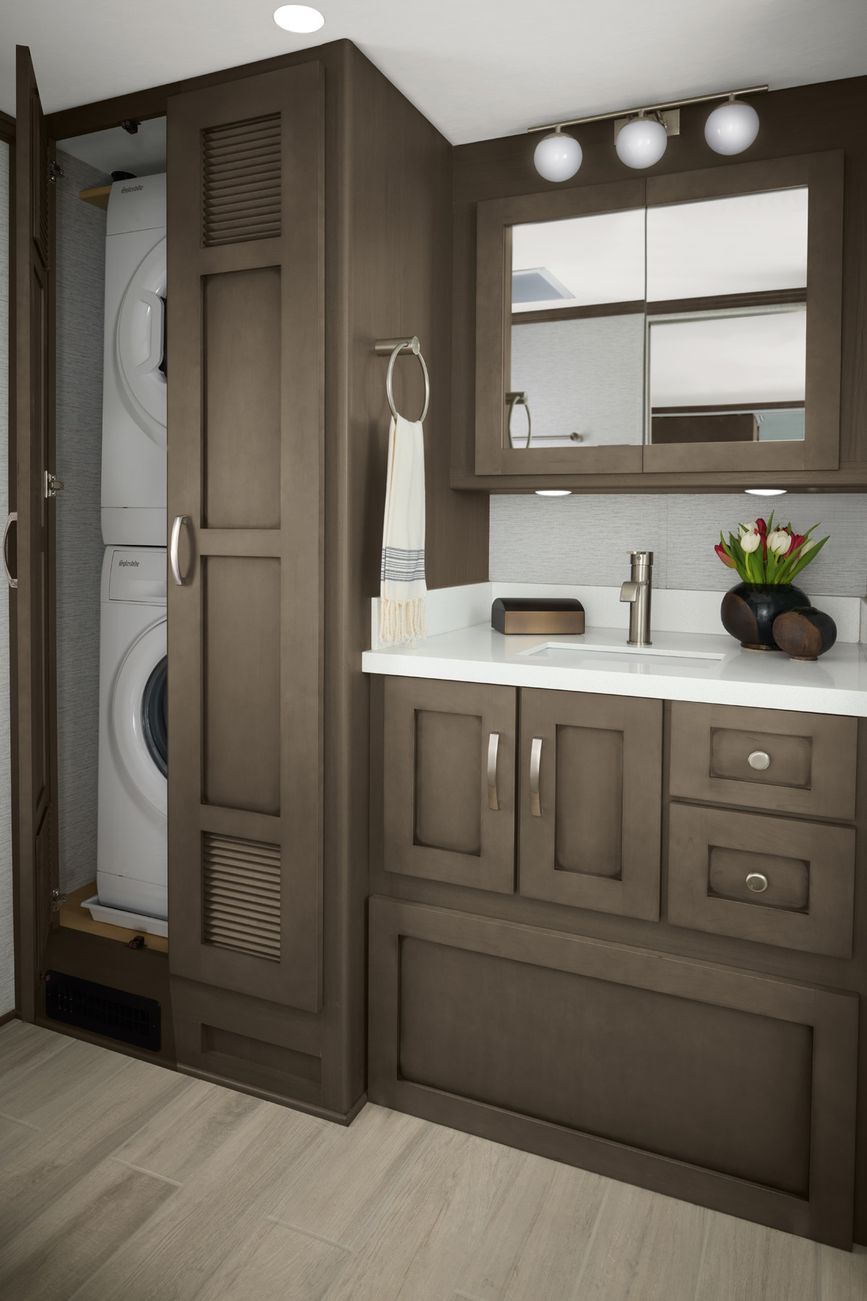 The Northern Star&#039;s beautiful bathroom with dark cabinetry and a stackable washer/dryer 