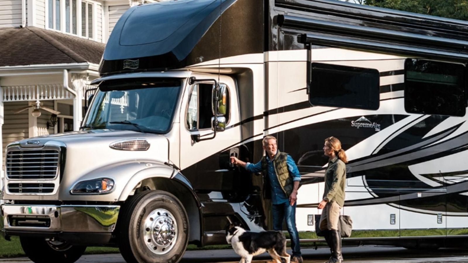 A couple and their dog in front of a Class A RV