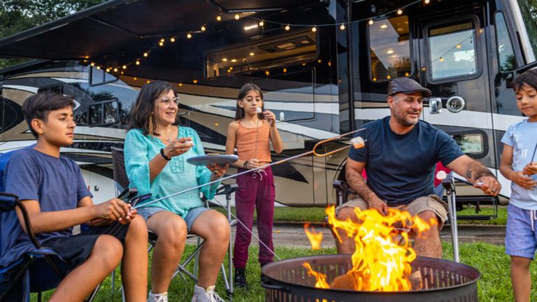 Family enjoying smores in front of an RV