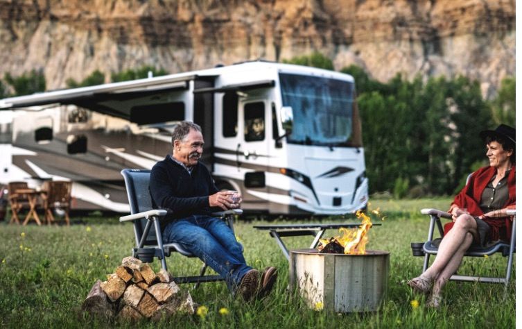 Couple enjoys a fire in front of an RV