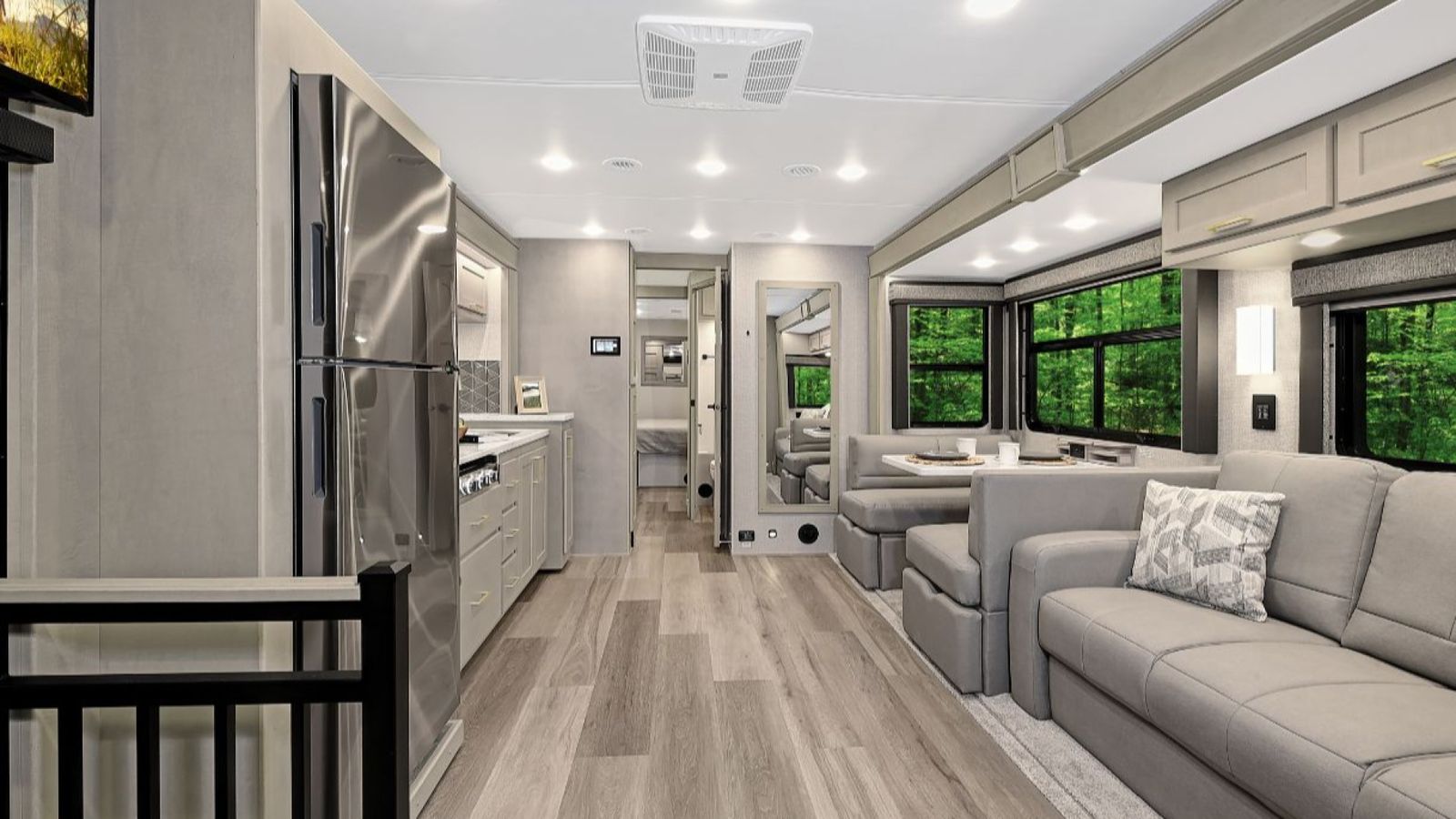 Interior of the 2026 Renegade Valencia with light wood cabinetry, stainless steel appliances, a full kitchen on the left, and a living area on the right