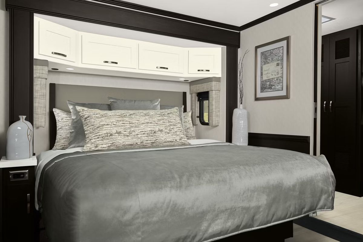 King-sized bed with silver coverlet and white painted overhead storage