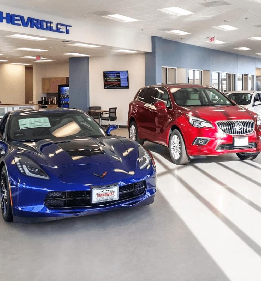 A blue sports car next to a red SUV in a car dealership lobby
