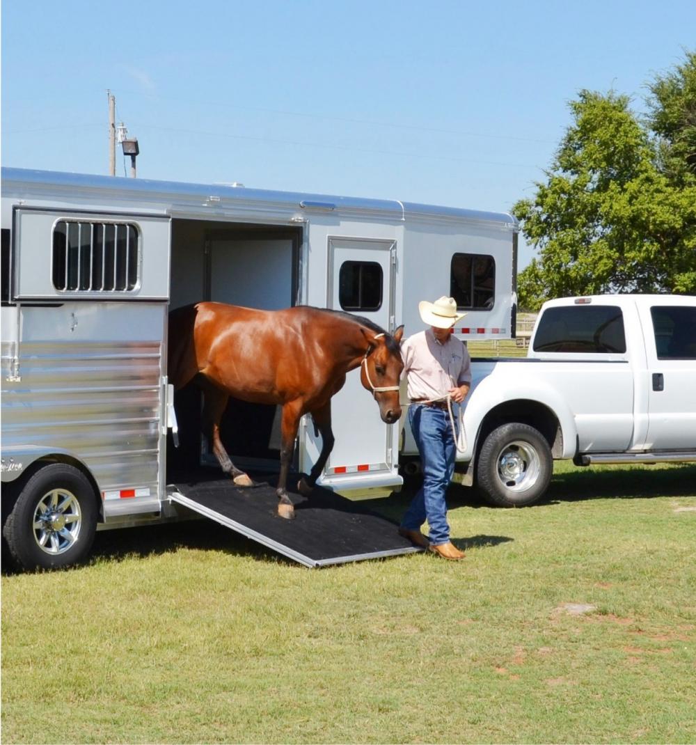 A man leading a horse out of a trailer